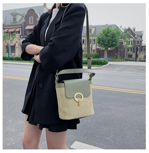 Straw bucket bag with green leather trim and gold ring detail styled on a model