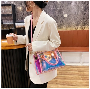 Detail of holographic PVC tote bag with pink leather handles in a cafe setting