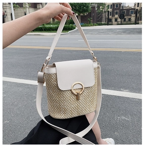 Detailed view of straw bucket bag with cream PU leather flap and gold ring buckle
