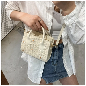Détail d'un sac cabas en paille beige avec broderie marguerite et bandoulière cuir
