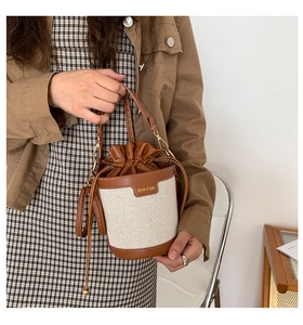 Detail of a chic bucket bag showing brown lychee leather and beige canvas textures