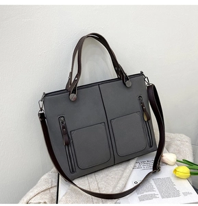 Detail of grey frosted leather tote bag with double zipper pockets and brown straps