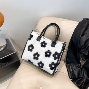 Detail van witte pluizige tote bag met zwarte bloemmotieven op een luxe bank