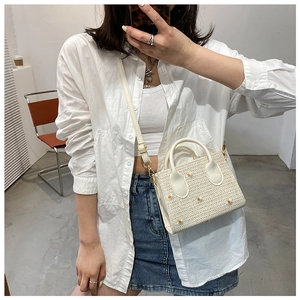 Selfie miroir montrant le sac en paille tissée avec broderie marguerite et anses blanches