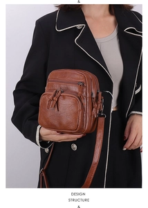 Detail view of caramel brown crossbody bag with multi-zipper layers and pebbled leather