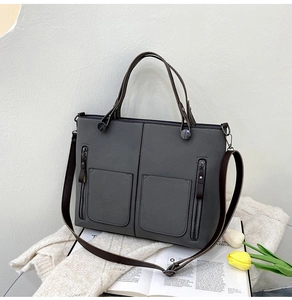 Detail of grey matte leather tote bag featuring side zip pockets and dual carry straps