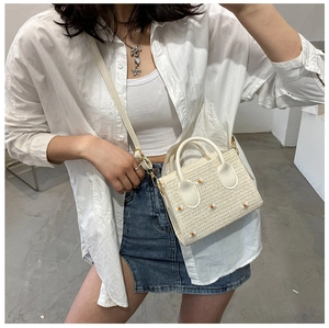 Détail du sac bandoulière en paille avec marguerites et poignées en cuir blanc