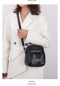 Detail of black multi-pocket crossbody bag showing pleated leather and zipper design