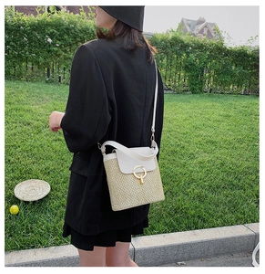 Detail of hand-woven straw bucket bag with white PU leather flap and gold ring lock