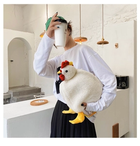 Detail of soft plush white chicken crossbody bag held by a model in a cozy cafe setting
