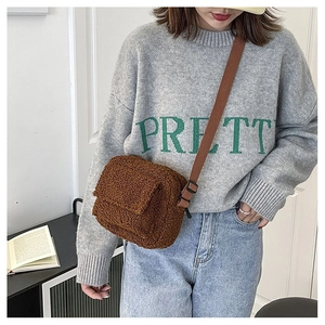 Détail de la texture d'un sac bandoulière en laine marron avec rabat et sangle réglable