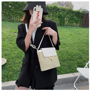 Detail of a straw crossbody bag with white leather flap and large golden circular buckle