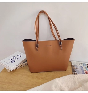 Détail du sac cabas en cuir marron avec texte FASHION et boucle en métal sur table en bois