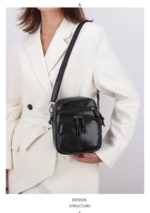 Detail view of black multi-pocket crossbody bag with vintage texture and long strap