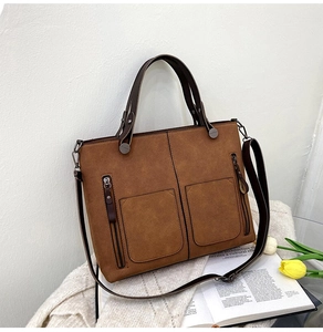 Brown matte suede tote bag with front zip pockets placed on books with tulips