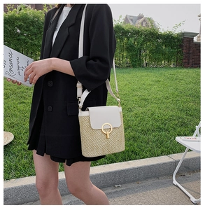 Detail of straw bucket bag with white leather flap and gold round metal lock