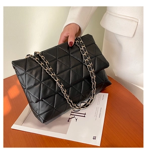 Détail du sac en cuir PU noir avec surpiqûres triangulaires et bandoulière dorée
