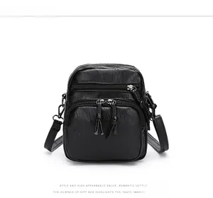 Detail of black pebbled leather crossbody bag with multiple zippers and adjustable strap