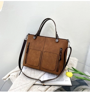 Detail of caramel suede tote bag featuring front dual pockets and decorative zippers