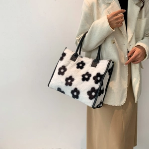Detail van pluche tote bag met bloemenpatroon en zwarte kunstleren handvatten