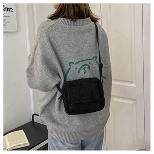 Mannequin portant un sac bandoulière en polaire noire avec sangle réglable dans un décor