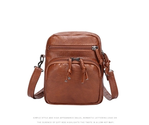 Detail of a brown lychee textured leather crossbody bag with three zipper compartments
