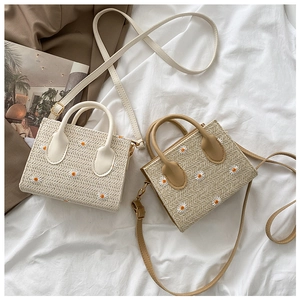 Détail de sacs cabas en paille avec broderie marguerite et poignées en cuir en deux couleurs