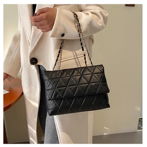 Détail du sac à bandoulière en cuir matelassé noir avec texture triangle et chaîne