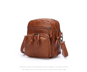 Detail of brown PU leather crossbody bag with multiple zipper pockets and wrinkled texture