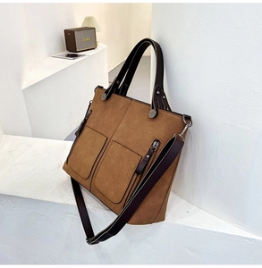 Detail of a brown frosted leather tote bag with dual pockets and metal zipper accents
