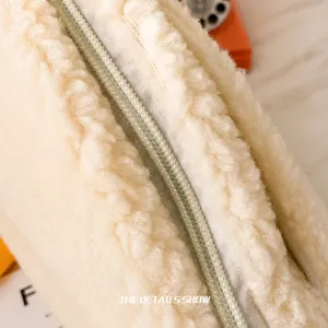 Close-up of smooth white plush fabric texture and sturdy zipper detail on the bag