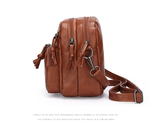 Macro detail of brown leather crossbody bag with triple zippers and tassel zipper pulls