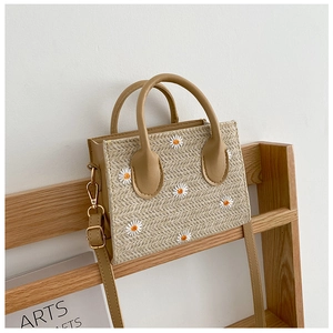 Détail du cabas en paille avec broderie marguerite et poignées en cuir marron