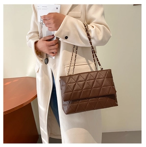 Sac à bandoulière matelassé marron foncé avec chaîne dorée sur une tenue femme