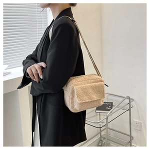 Vue détaillée du sac bandoulière en laine d'agneau crème porté avec un blazer noir