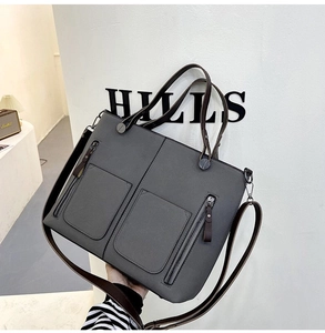 Detail view of a grey matte leather tote bag featuring multiple zipper pockets and straps