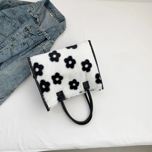Detail van witte pluche draagtas met bloemmotieven en duurzame zwart kunstleren hengsels
