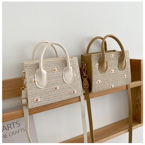 Sacs cabas en paille avec broderies marguerites et anses en cuir sur étagère