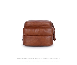 Detail view of brown leather bag with multi-layer accordion design and tassel zipper