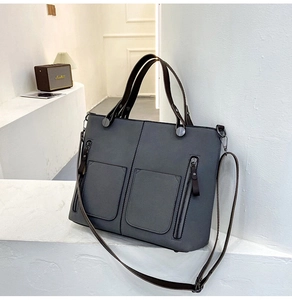 Detail view of grey frosted leather tote bag showing front zipper pockets and texture