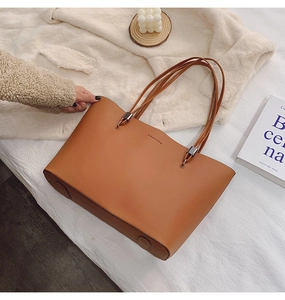 Détail d'un sac cabas marron en similicuir avec quatre fines lanières sur tapis blanc doux