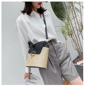 Detail of straw bucket bag with black leather flap and golden ring hardware on model