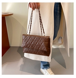 Détail du sac en cuir matelassé marron foncé avec coutures triangles et chaîne dorée