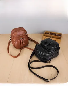 Detail view of multi-pocket crossbody bags in brown and black with grainy leather texture