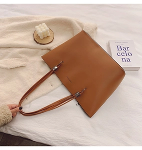 Détail d'un sac cabas en cuir PU marron avec texte FASHION sur fond textile blanc doux