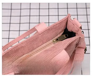 Detail view of smooth bronze metal zipper on pink corduroy tote bag with black lining