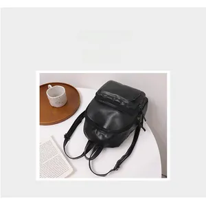 Detail of black pebbled leather backpack showing the front zipper pocket and main closure