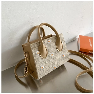 Détail d'un sac à main en paille beige avec broderie marguerite et cuir chic