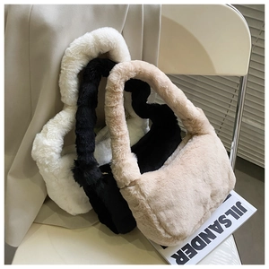 Vue détaillée de sacs à bandoulière en fausse fourrure blanche, noire et beige sur une chaise