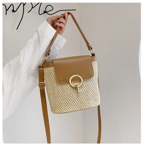 Detail of straw bucket bag featuring natural woven texture and brown leather flap